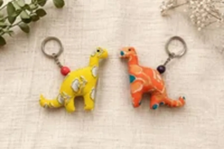 Two handmade dinosaur key charms in yellow and orange prints
